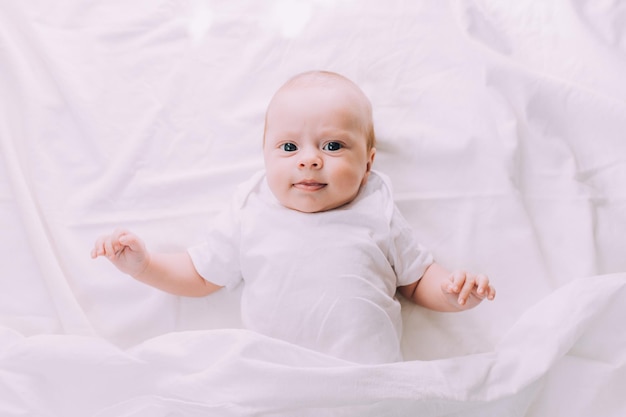 The baby is lying in his crib and looking at the camera A happy child Children's article