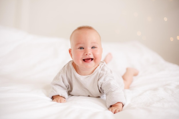 The baby is lying at home on the bed smiling