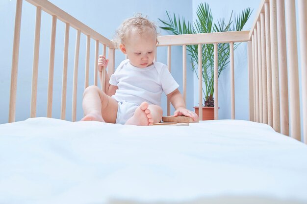 아기가 유아용 침대에서 큐브 놀이를 하고 있습니다. 텍스트 또는 어린이 제품을 위한 공간을 복사합니다.