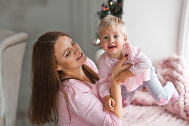 The baby is playing with her mother lying on a pink blanket 2010