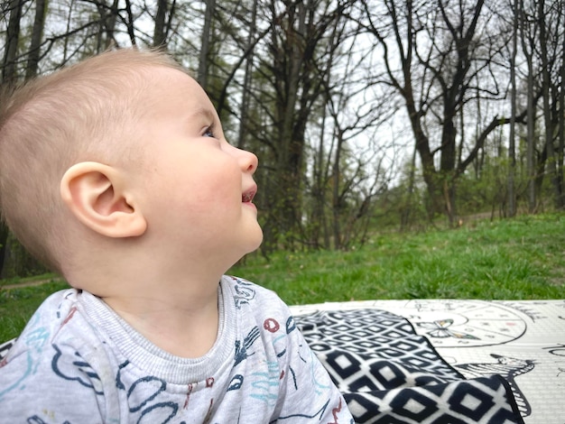 Foto un bambino è seduto su una coperta di fronte ad alcuni alberi