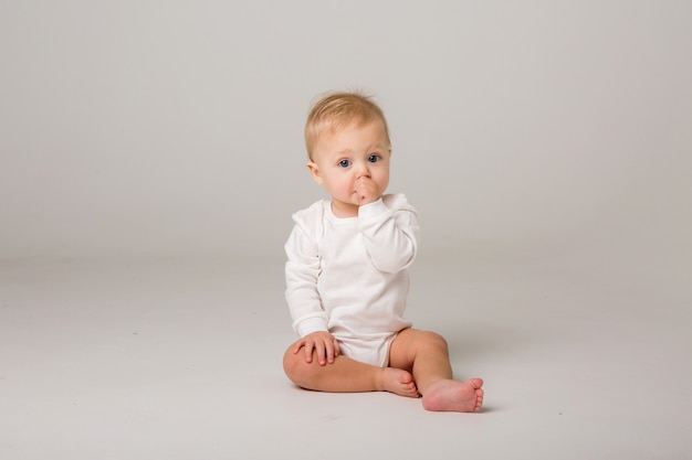 Foto il bambino è seduto su uno sfondo chiaro