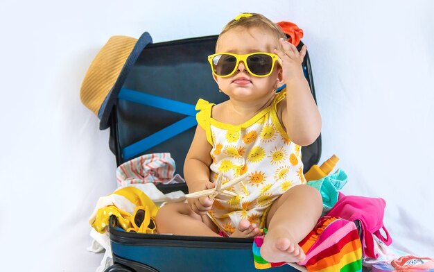 Baby is sitting in a suitcase, getting ready for a travel