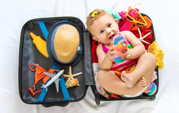 Baby is sitting in a suitcase, getting ready for a travel