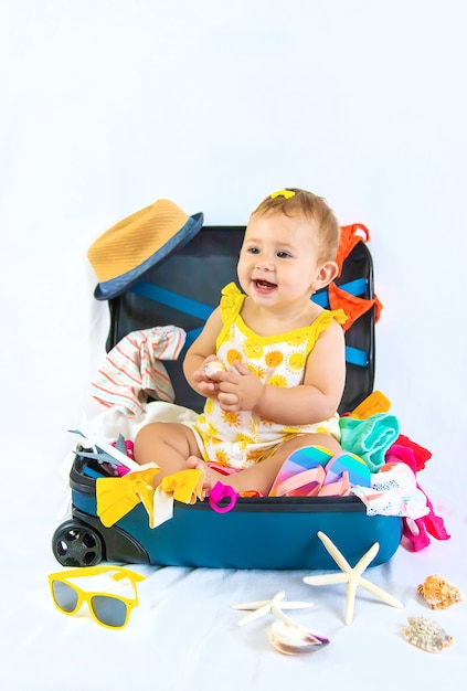 Baby is sitting in a suitcase, getting ready for a travel