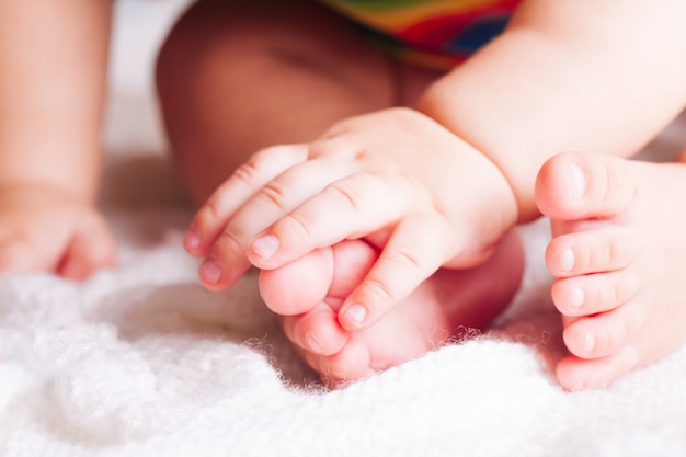 Il bambino è seduto sul tessuto. mani e piedi da vicino