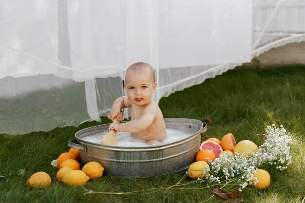 the baby is sitting in a tub on the grass in the yard