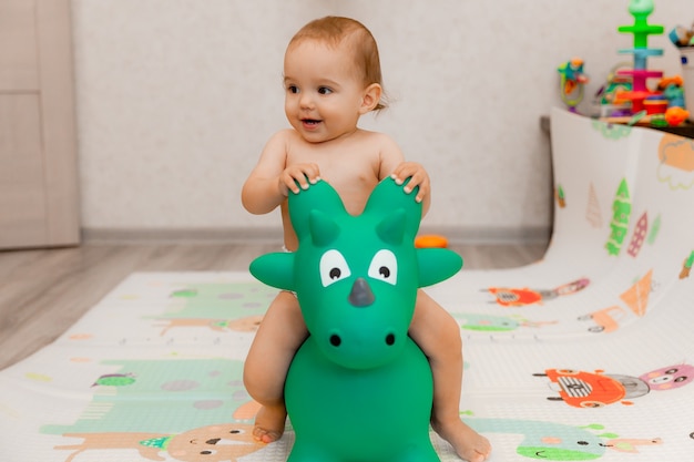 赤ちゃんは自分の部屋でドラゴンの形をしたガーニーで揺れています。おもちゃのドラゴン。