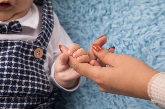 a baby is wearing a checkered shirt and a button is standing next to her mothers hand