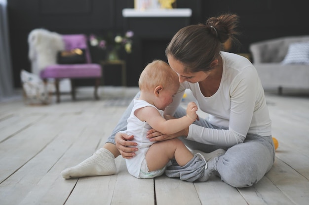 baby jongen huilt moeder troost en medelijden zijn zoon op de vloer in een echt stijlvol interieur