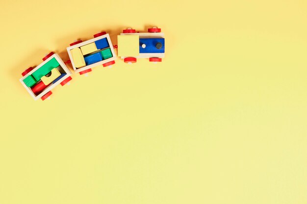 Baby kid toy wall. Top view to wooden toy train with colorful blocks on yellow wall.