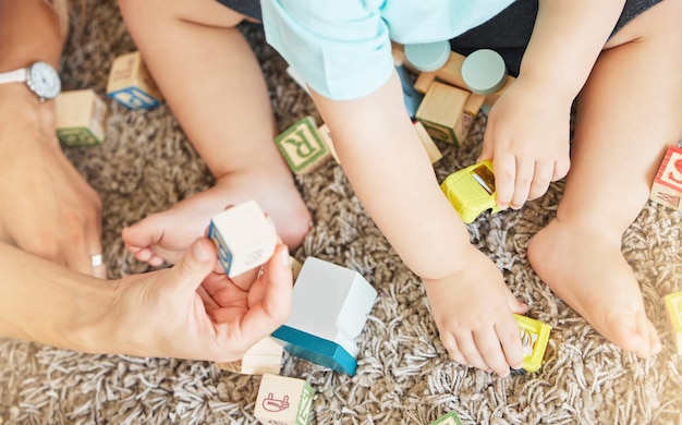 Baby kids hands building blocks and play learning for fun education and healthy motor skills development on home carpet floor Above closeup parent and child playing with creative toys and games