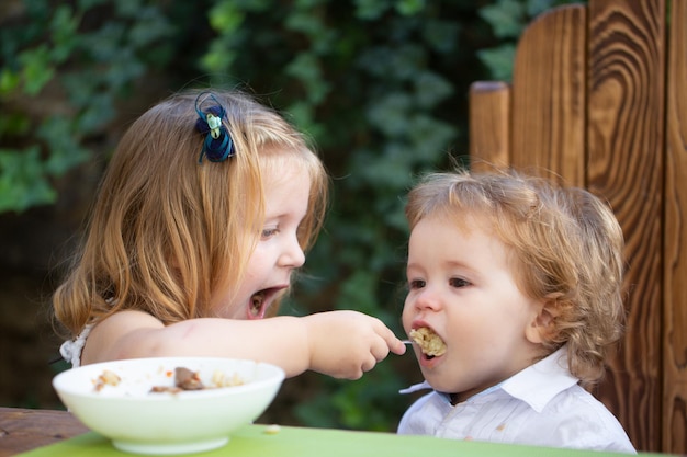 Baby kind eet voedsel kleine meisje zus voedt baby