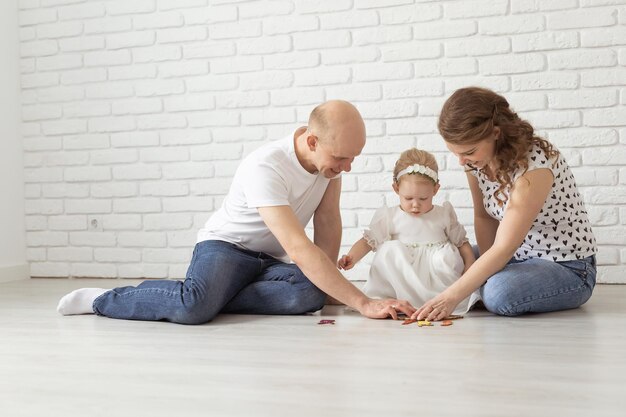 Baby kind met gehoorapparaten en cochleaire implantaten speelt met ouders op de vloer doof en