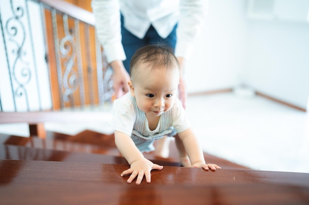 Baby kind persoon of peuter leren lopen op de vloer in een gevoel van gelukkig plezier thuis kleine kleine jongen zijn gezonde stap kruipen in de kindertijd levensstijl ondersteuning door familie