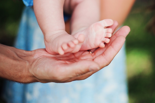 Baby kleine voeten in handen van de ouders. Zomerdag.