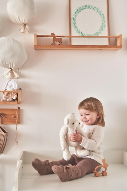 Photo baby in knitted clothes in children room nursery interior