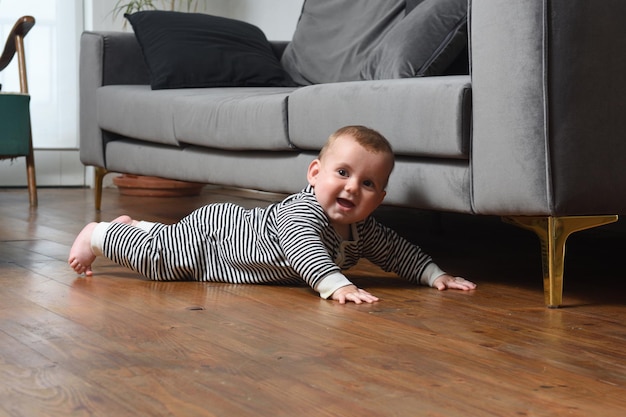 Baby kruipt thuis op de grond, met een houten vloer die kijkt en lacht