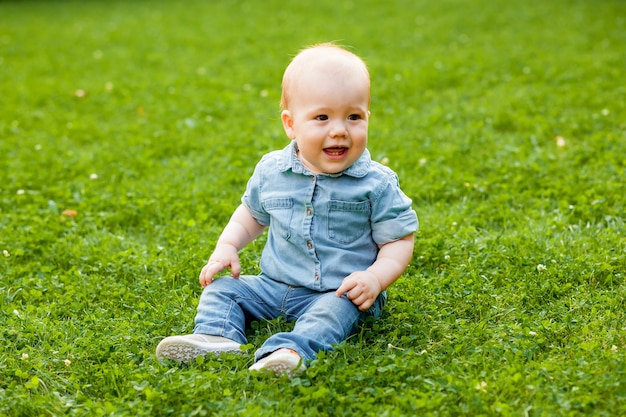 赤ちゃんは芝生の上に座って笑う