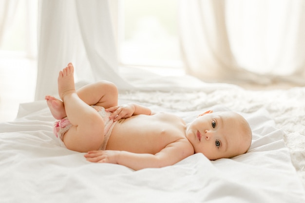 Bambino posa sul letto bianco