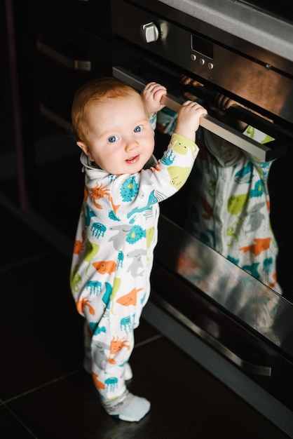 The baby learns to stand near the oven in the kitchen Little nine months baby boy stands with support at home Toddler just learnt how to stand on her feet Baby taking first steps