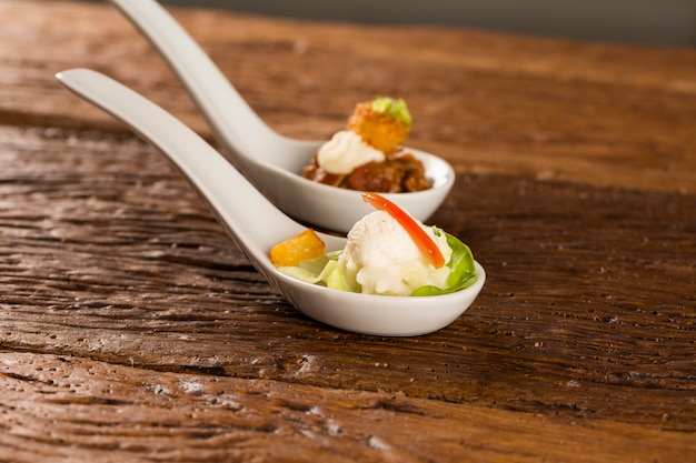 Baby lettuce salad, cherry tomatoes, palm hearts, cauliflower sauce, fried manioc and salted whipped cream in a spoon. Taste gastronomy fingerfood