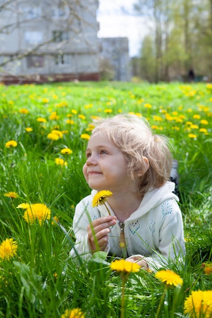 Baby lies in meadow with dandelions