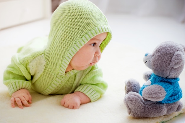 Baby liggend kijken naar speelgoed Beer