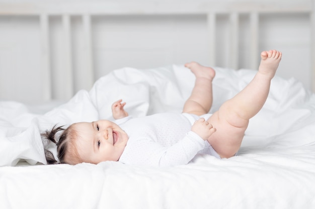 Baby liggend op het bed thuis met zijn voeten omhoog, het concept van een gelukkige liefdevolle familie en kinderen