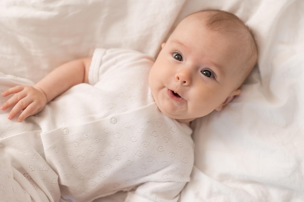 Baby ligt op een bed met een wit laken waarop 'baby' staat