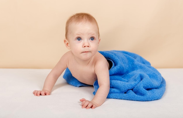 파란색 담요 아래에서 카메라를 보고 있는 아기 어린 시절과 아기 돌보기