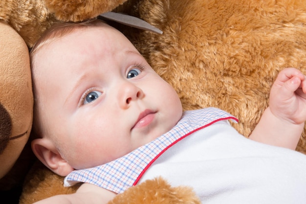 Baby lying in bed with a plush teddy bear