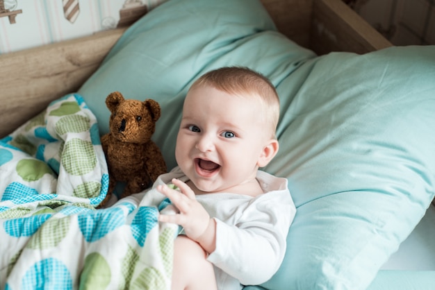 baby lying in bed with a plush teddy bear