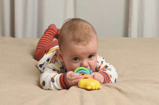 写真 おもちゃで遊んでベッドに横たわっている赤ちゃん、