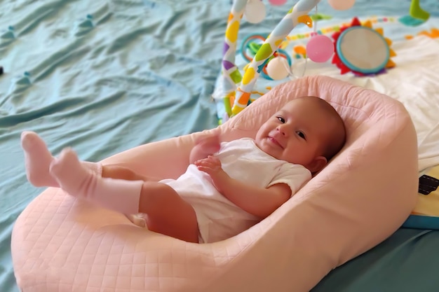 Baby lying in a special orthopedic mattress on a bed and smile