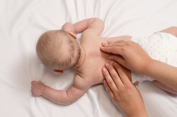 Photo baby massage, close-up hands on baby back top view