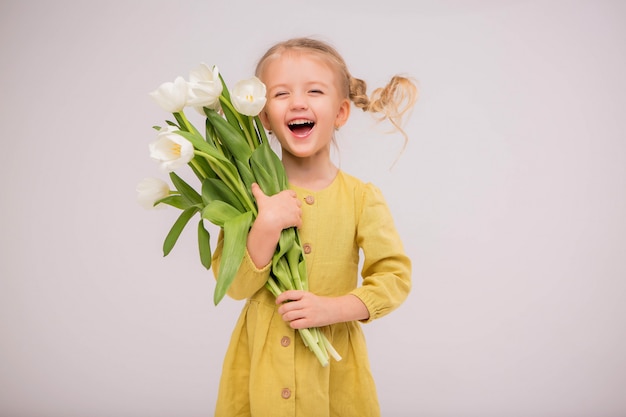 baby meisje blonde met een boeket tulpen op een lichte achtergrond