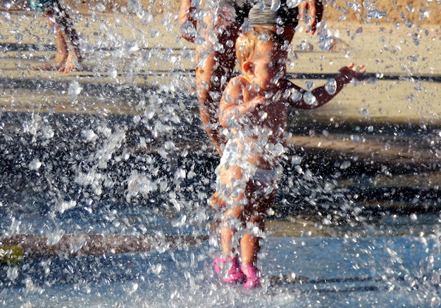 Foto baby meisje geniet van het spetteren van water in de fontein tijdens de zomer