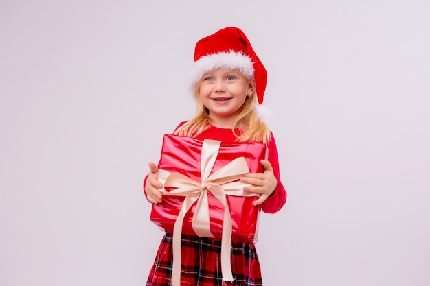 baby meisje in Kerst muts rode geschenk doos op witte muur te houden