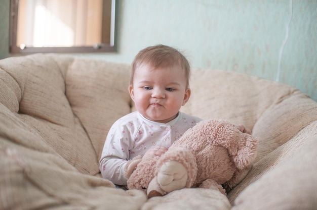 Baby meisje met teddybeer op de bank thuis