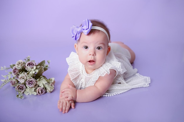 Baby meisje poseert en glimlacht op paarse achtergrond