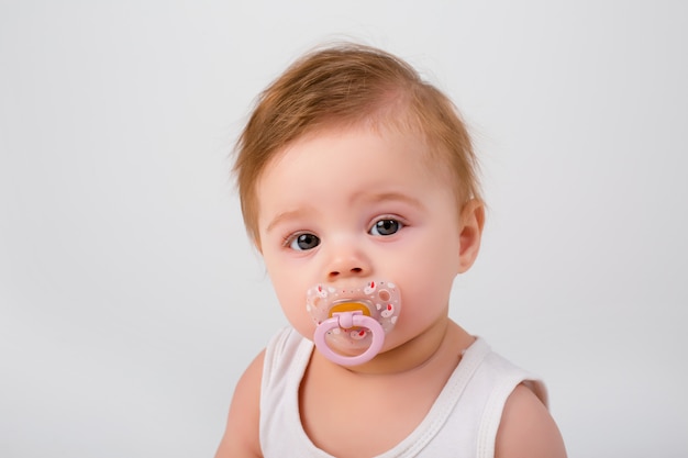Baby met een fopspeen in zijn mond op een witte achtergrond