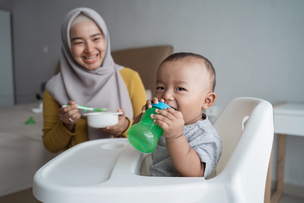 Baby met fles water zittend op een stoel