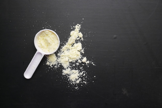 Baby milk powder and spoon on black background