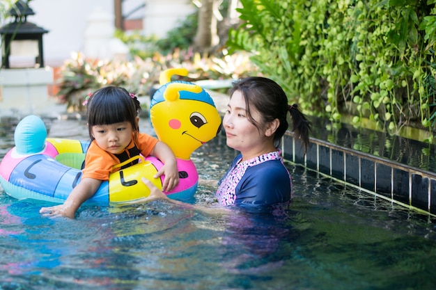 Bambino e madre che giocano acqua in piscina