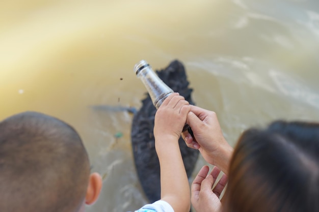 魚の餌の瓶を持っている赤ちゃんと母親の手