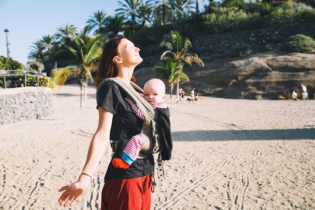 Baby and mother on sea at summer day Happy family walking on nature outdoors