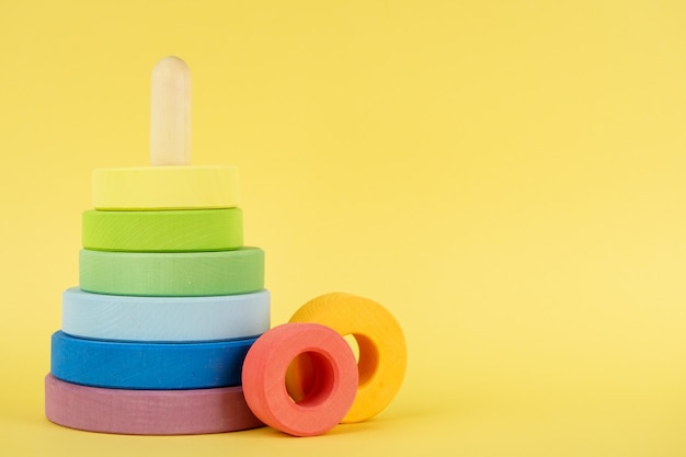 Baby multi-colored pyramid on yellow background, children education