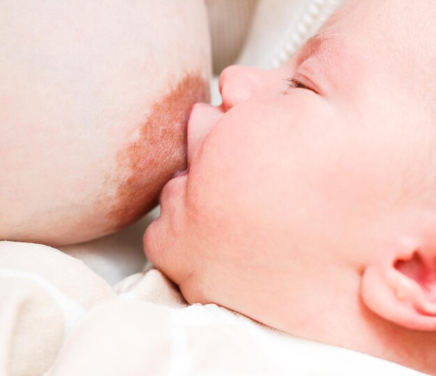 The baby naked lies on her back on a white sheet and shows emotions Selective focus on the baby39s head The child looks directly at the camera Closeup