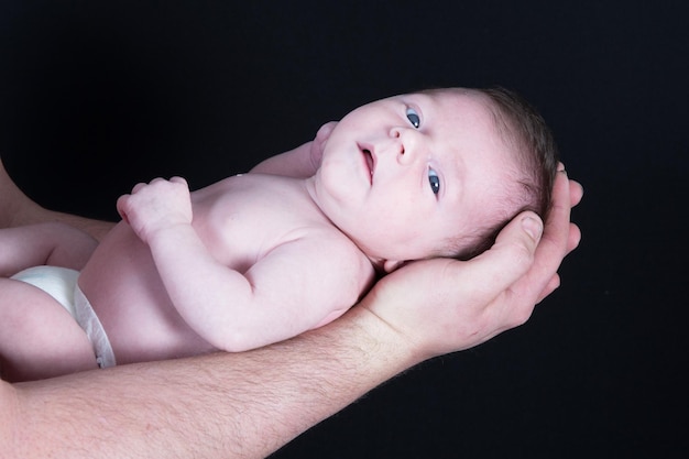 Baby newborn child lying on the arm father